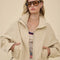 model wearing light khaki cropped jacket with stand up collar and elastic bottom