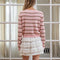 back view of model wearing light pink cardigan with thin brown and white striped