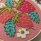 up close of pink embroidery kit with all over strawberry and strawberry leaves