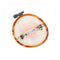back view of pink heart cross-stitch french barrette with brown embroidery hoop and iridescent base