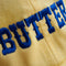 pastel yellow dad hat with blue 'BUTTER' across the front
