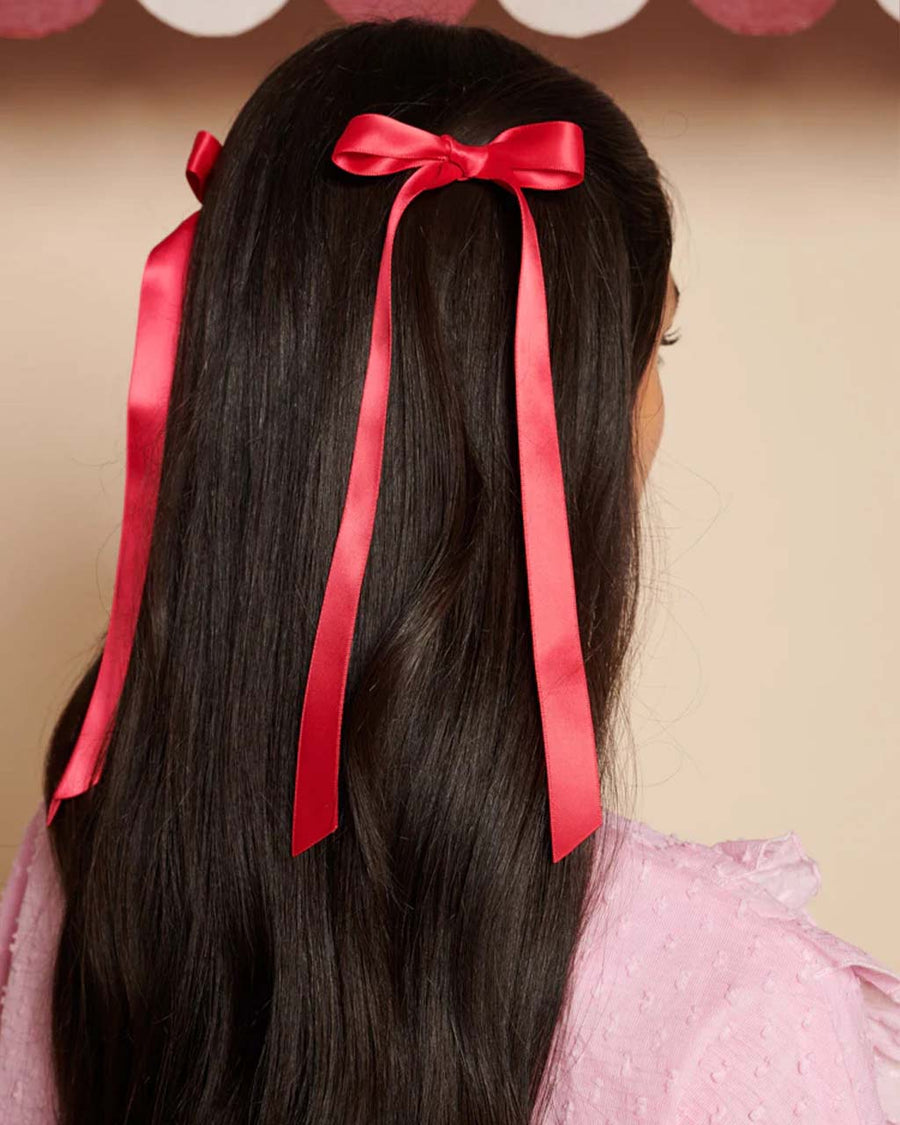 side view of model wearing silky cranberry colored hair bows