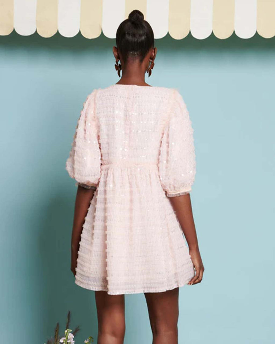 back view of model wearing light pink textured mini dress with sequin detail