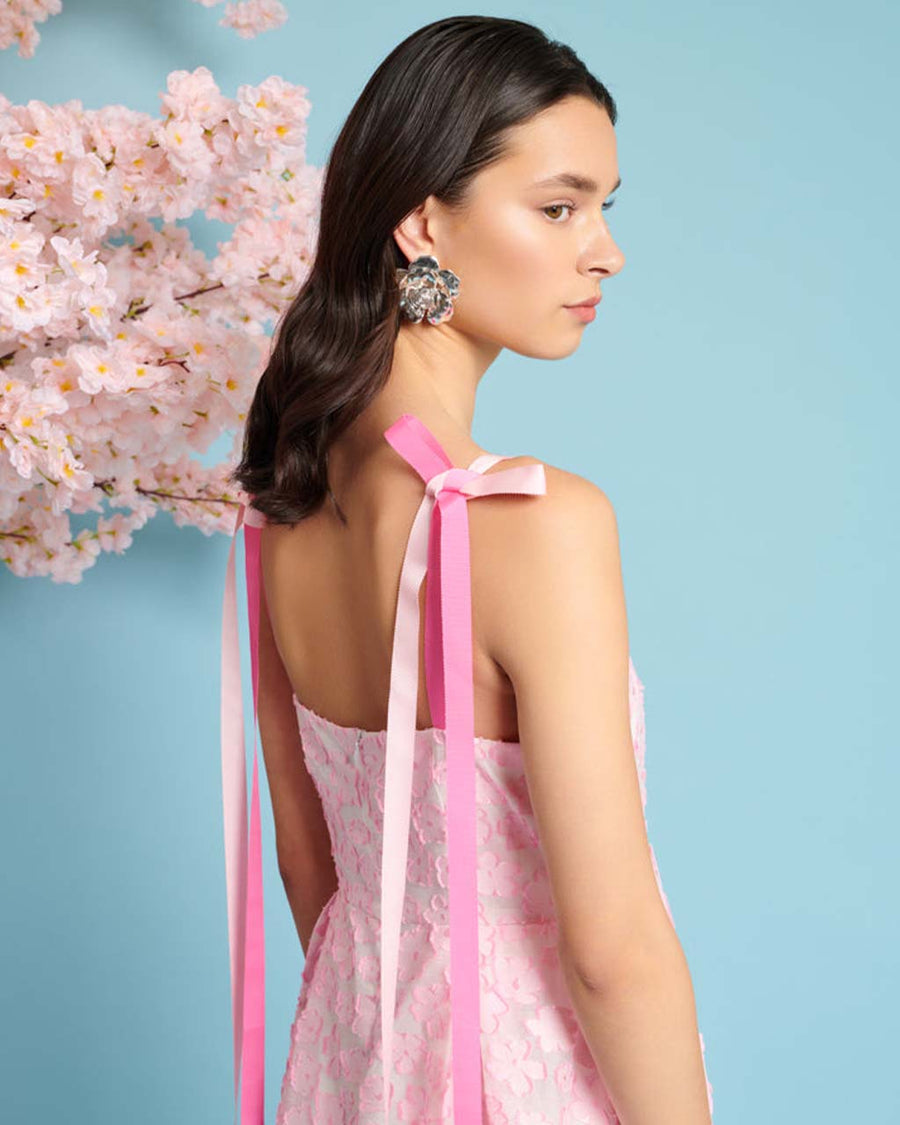 up close of model wearing pink applique midi dress with ribbon bow straps