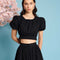 model wearing black jacquard crop top with slight puff short sleeves and tie back
