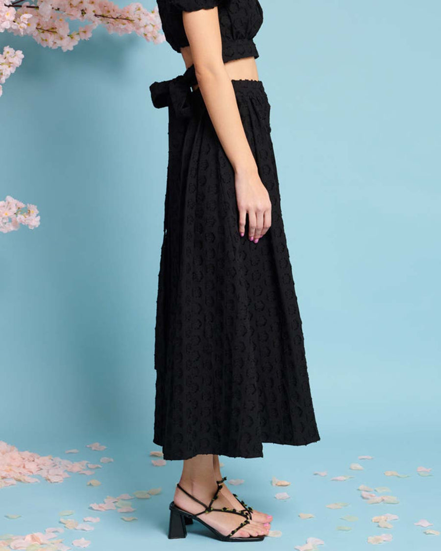 side view of model wearing black jacquard button front midi skirt