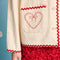 up close of model wearing natural jacket with red ric rac trim and embroidered heart detail on front patch pockets