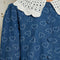 up close of model wearing denim midi dress with white heart pattern and white crochet collar