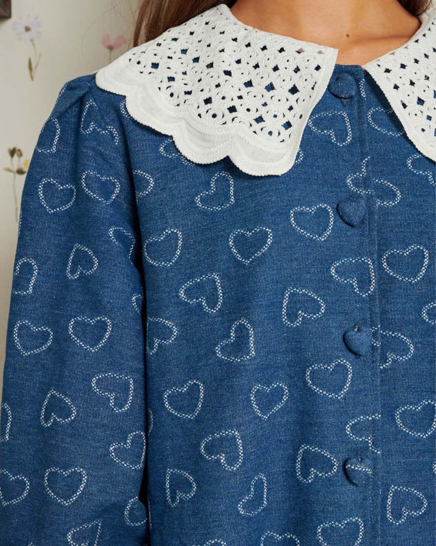 up close of model wearing denim midi dress with white heart pattern and white crochet collar