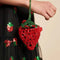 side view of model holding beaded strawberry shaped mini bag