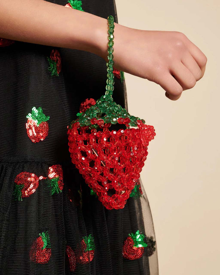 side view of model holding beaded strawberry shaped mini bag