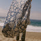 model waving cream and dusty blue abstract palm tree and sun design turkish towel on the beach