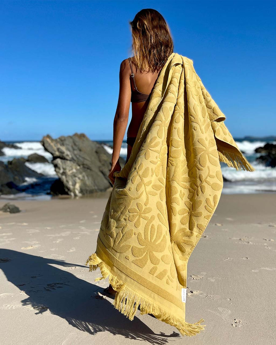 model carrying golden mustard floral textured beach towel