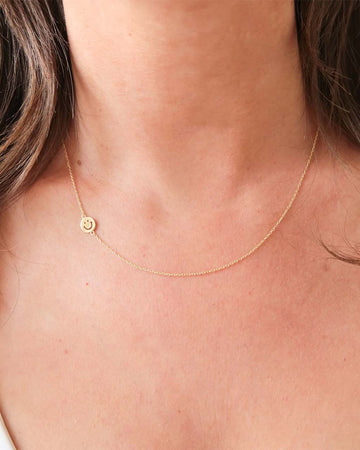 model wearing gold smiley face necklace