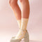 model wearing cream scalloped socks with glittery star print and glittery heels