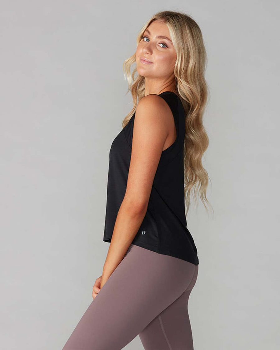 side view of model wearing black active tank with hi-lo hem and muscle tank sleeves