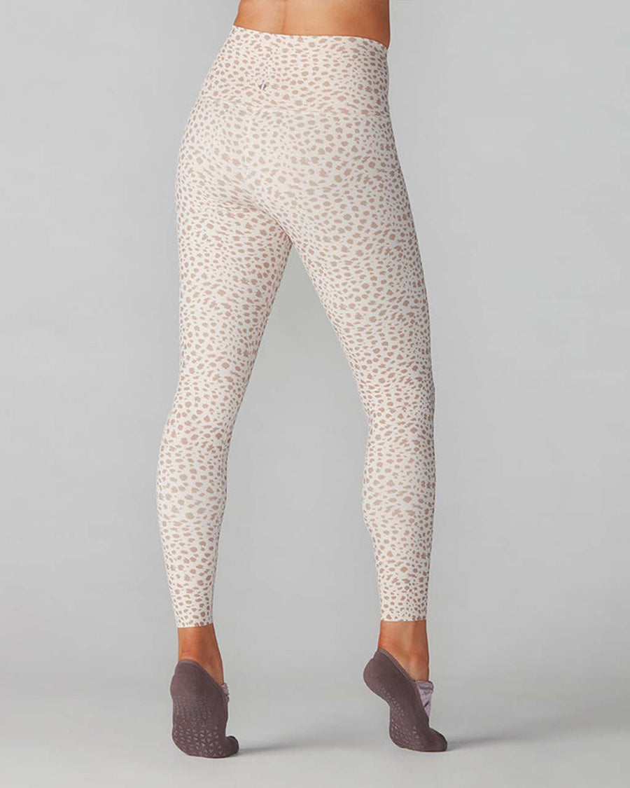 back view of model wearing white high waisted active leggings with brown spotted print