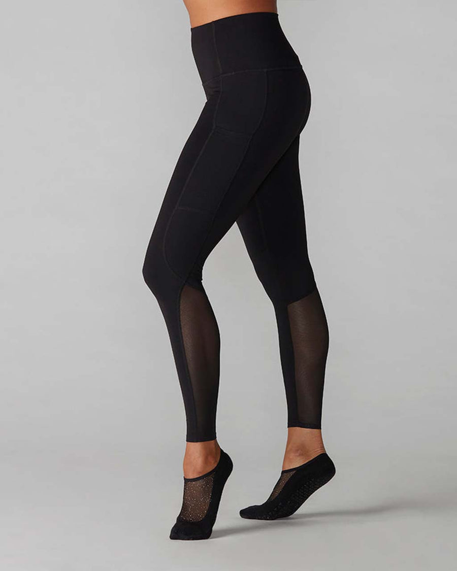side view of model wearing black leggings with mesh legs and side pockets