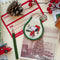 cream patch keychain with green trim and snoopy in a red nightshirt and night cap carrying a candle on a background with pinecone, cranberries and pine branches