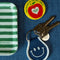 denim patch keychain with white smiley face and trim next to NYC pin and striped tray
