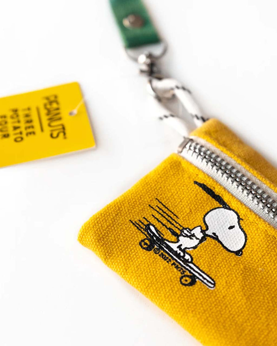 up close of golden yellow zip lanyard wallet with snoopy skateboarding