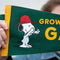 green pennant flag with snoopy graphic and gold trim and 'grow a garden' typography