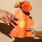 model holding orange flower paper vase