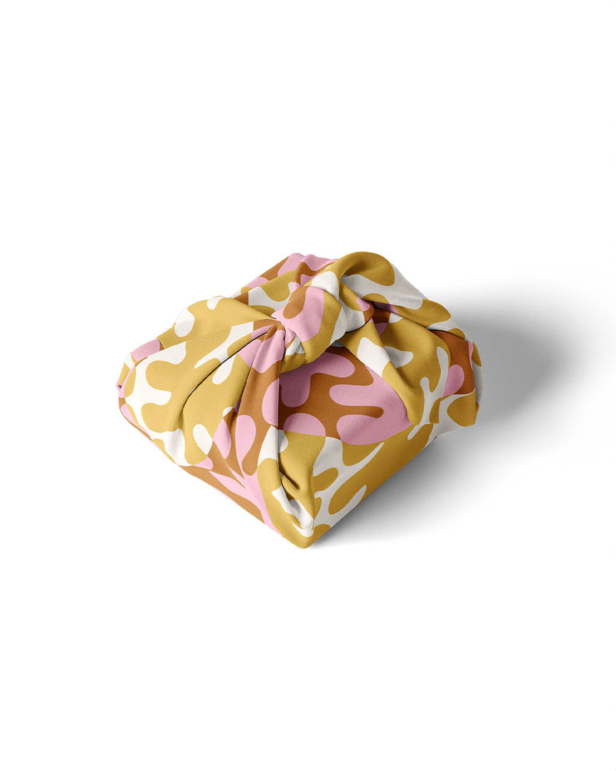yellow, pink and green blob fabric wrap with the JOY! across the front wrapped around a gift