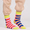model wearing blue, orange, coral, lavender striped socks with yellow trim