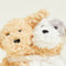 up close of brown dog and white + grey dog hugging warmie plushes