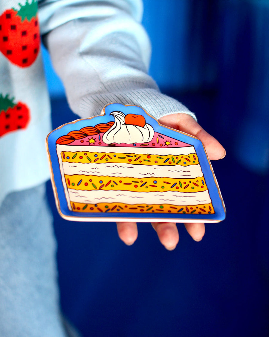 model holding pink and yellow layered cake trinket tray with blue ground
