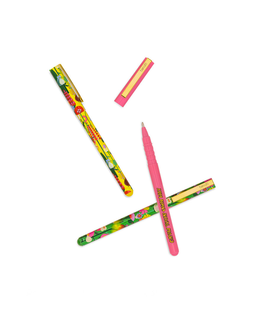 scattered set of three pens: yellow geometric floral, pink 'grow your own way', and green geometric floral