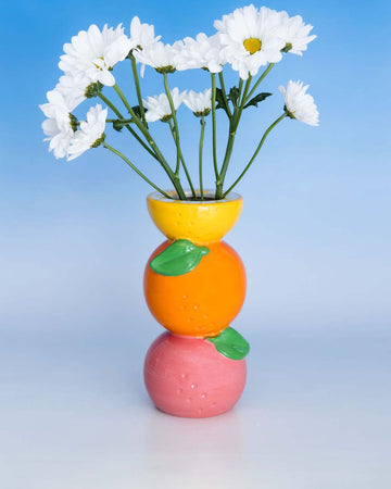 Stacked citrus vase with white daisies inside