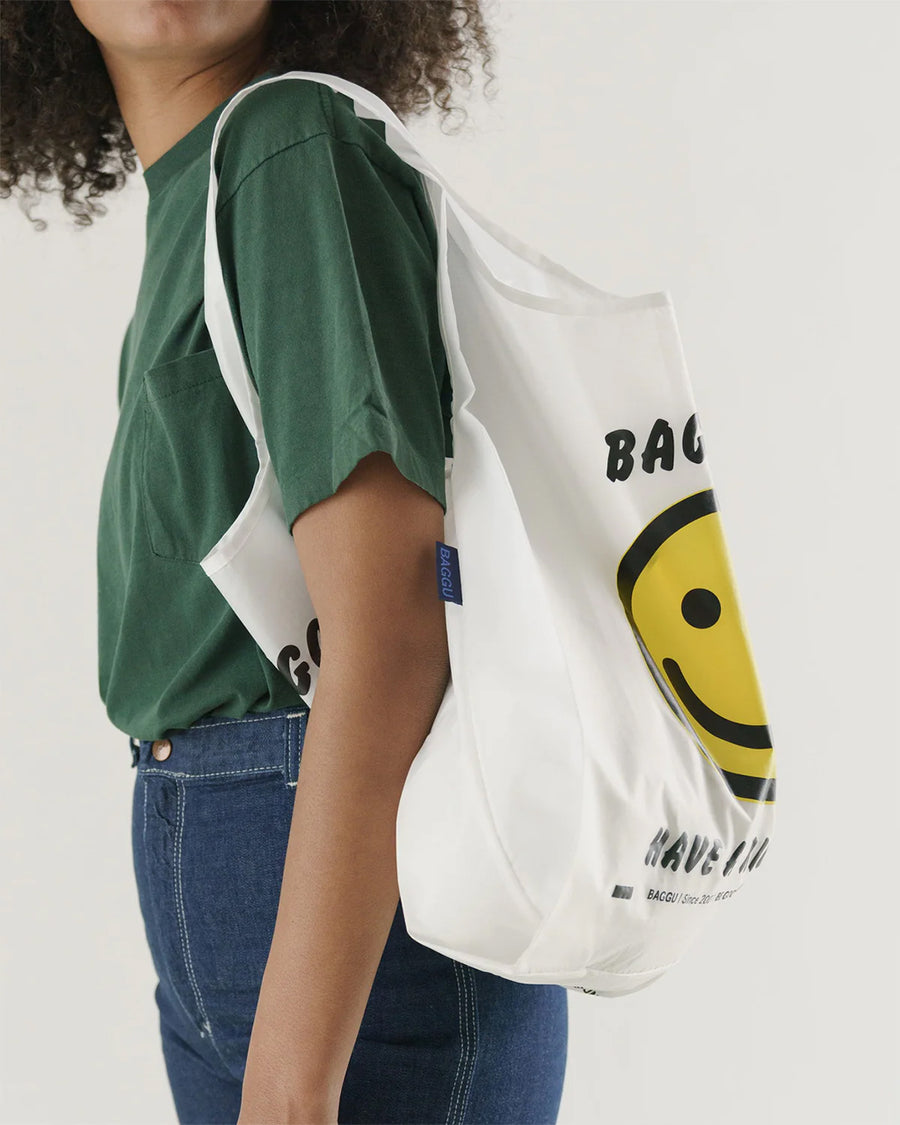 model carrying white standard baggu with yellow smiley and 'baggu- have a nice day!' text
