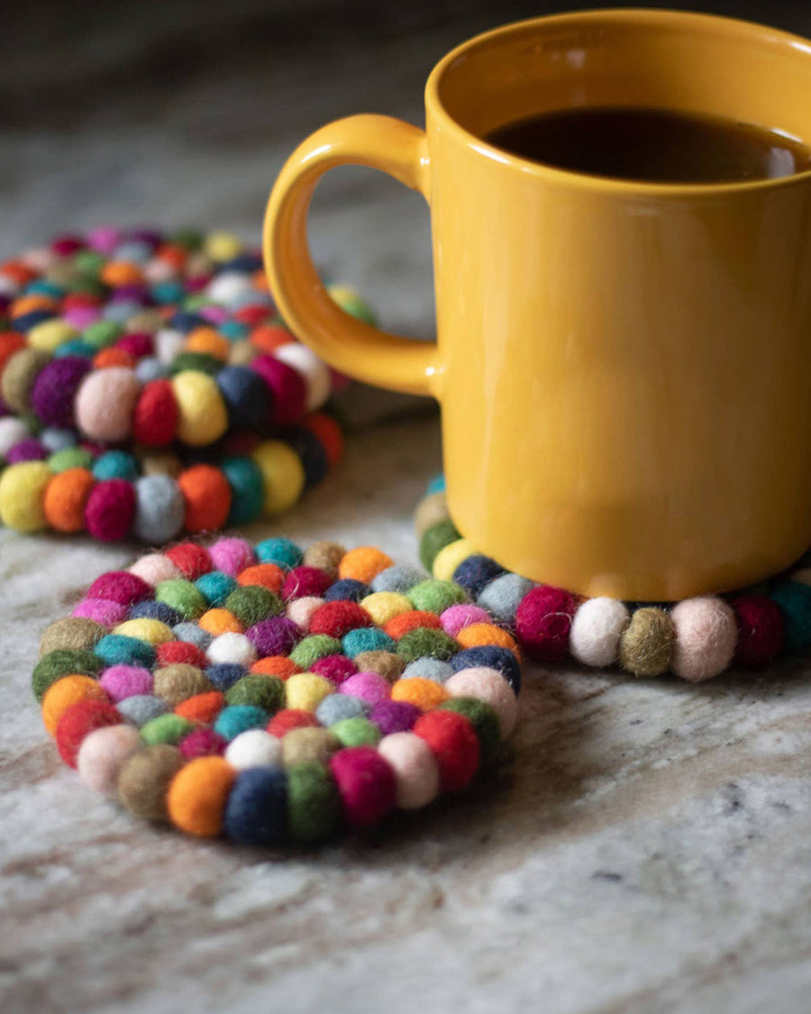 set of 4 colorful pom coasters with a coffee cup on them
