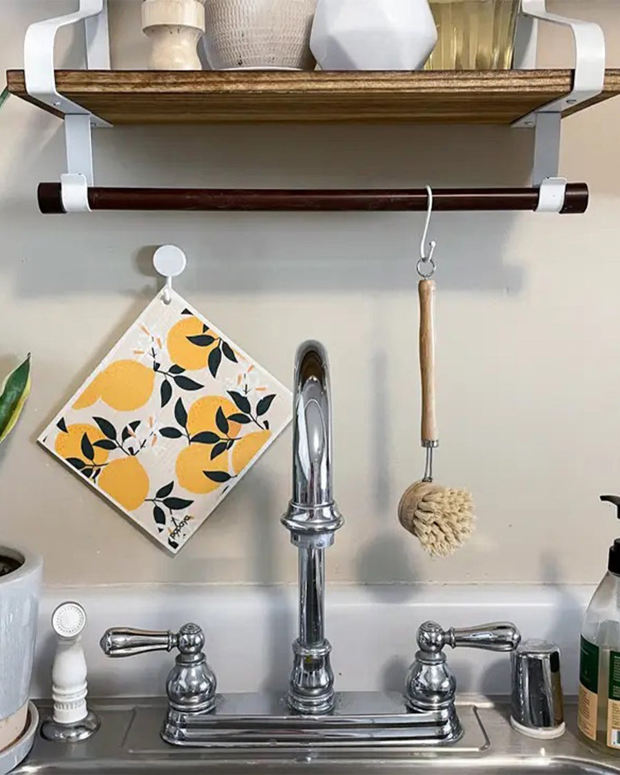 lemon print swedish dish cloth hanging over a kitchen sink