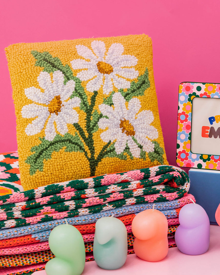 editorial image of square throw pillow with yellow ground and daisy flowers throughout