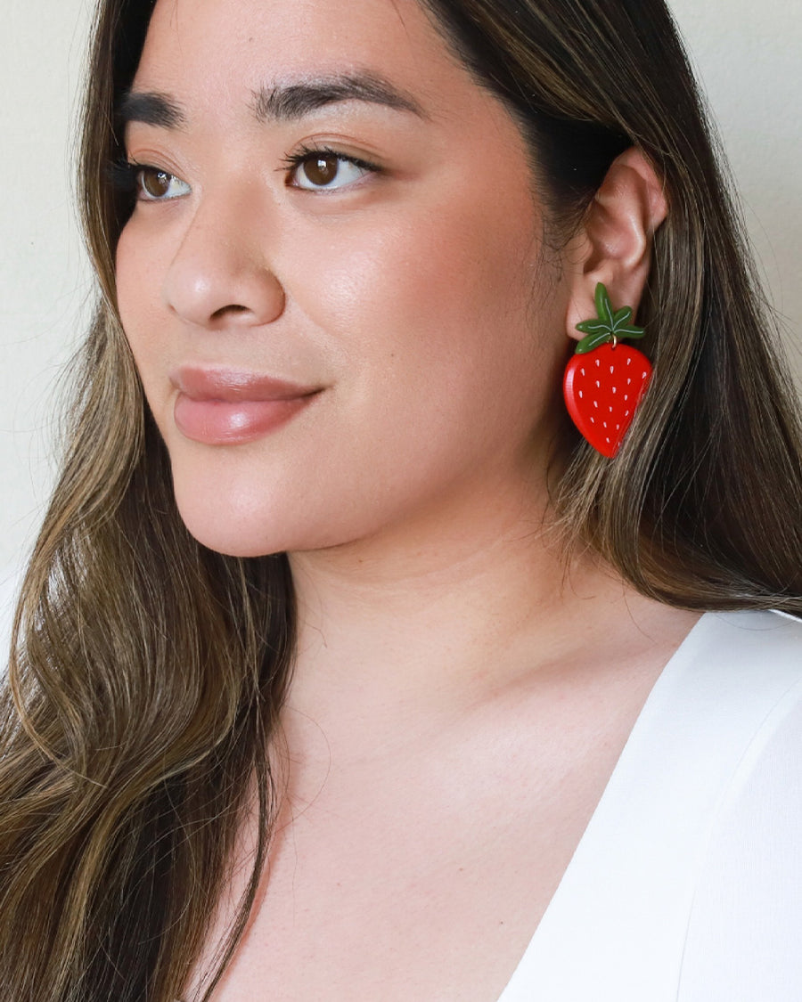 model wearing large strawberry earrings