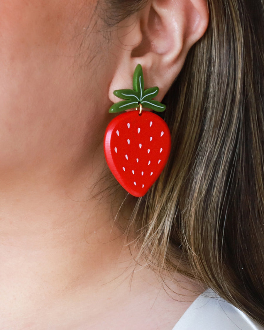 up close of model wearing large strawberry earrings