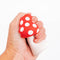 model squishing mushroom shaped de-stress ball with white stem and red top with white polka dots