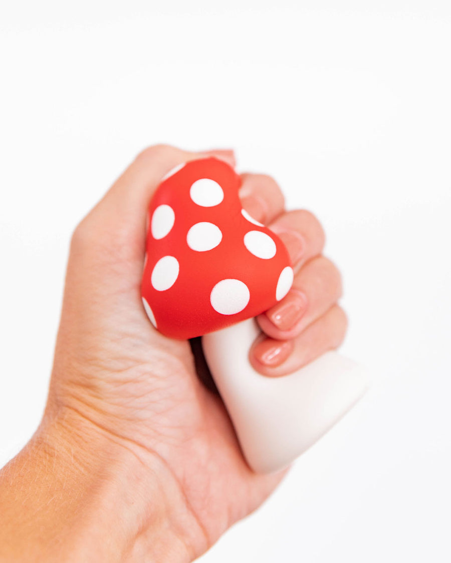 model squishing mushroom shaped de-stress ball with white stem and red top with white polka dots
