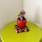 strawberry vase with daisies inside and on a table