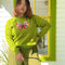 Woman wearing green long sleeved sweater with butterfly on the front