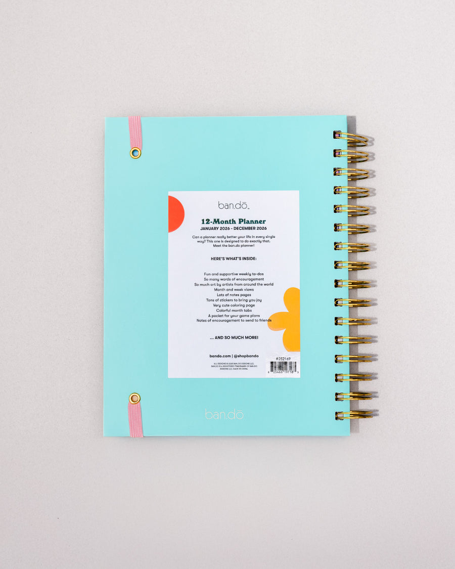 back view of sky blue 12-month large planner with white 'a joy to be around' and light pink elastic closure