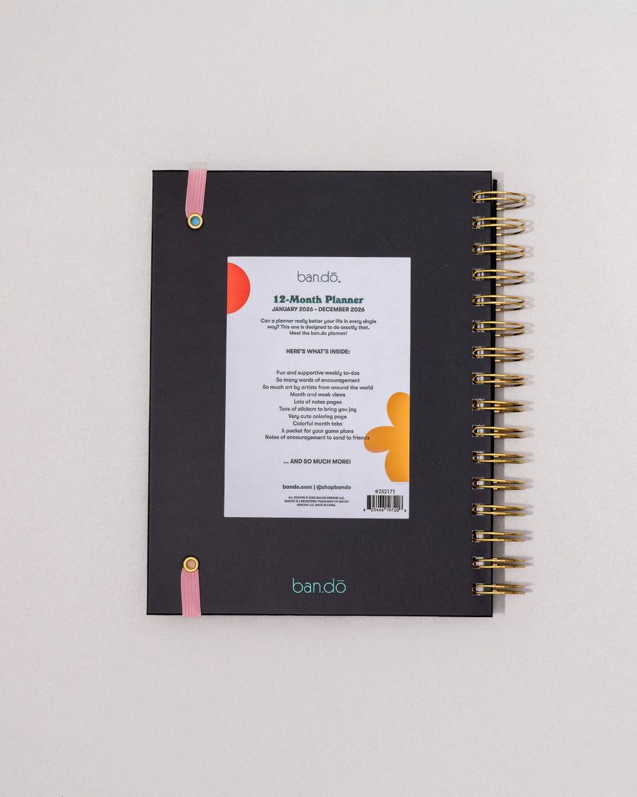 back view of black 12-month planner with colorful 'i'm thrilled to be here' and pink elastic closure