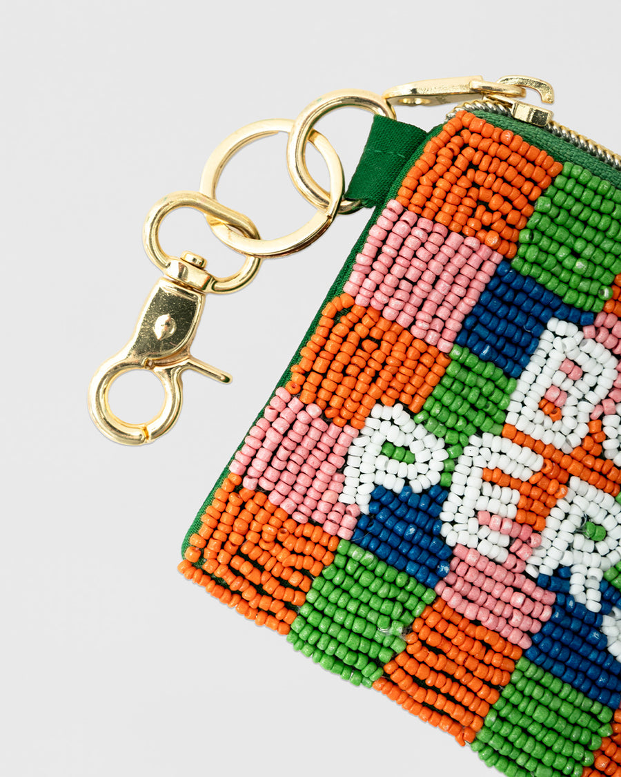 up close of colorful checkered beaded coin pouch with white beaded 'book person' and removable gold hardware