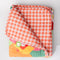orange and cream gingham back side of quilted blanket with colorful ill and house print with 'house has my favorite places and faces' typography in the center