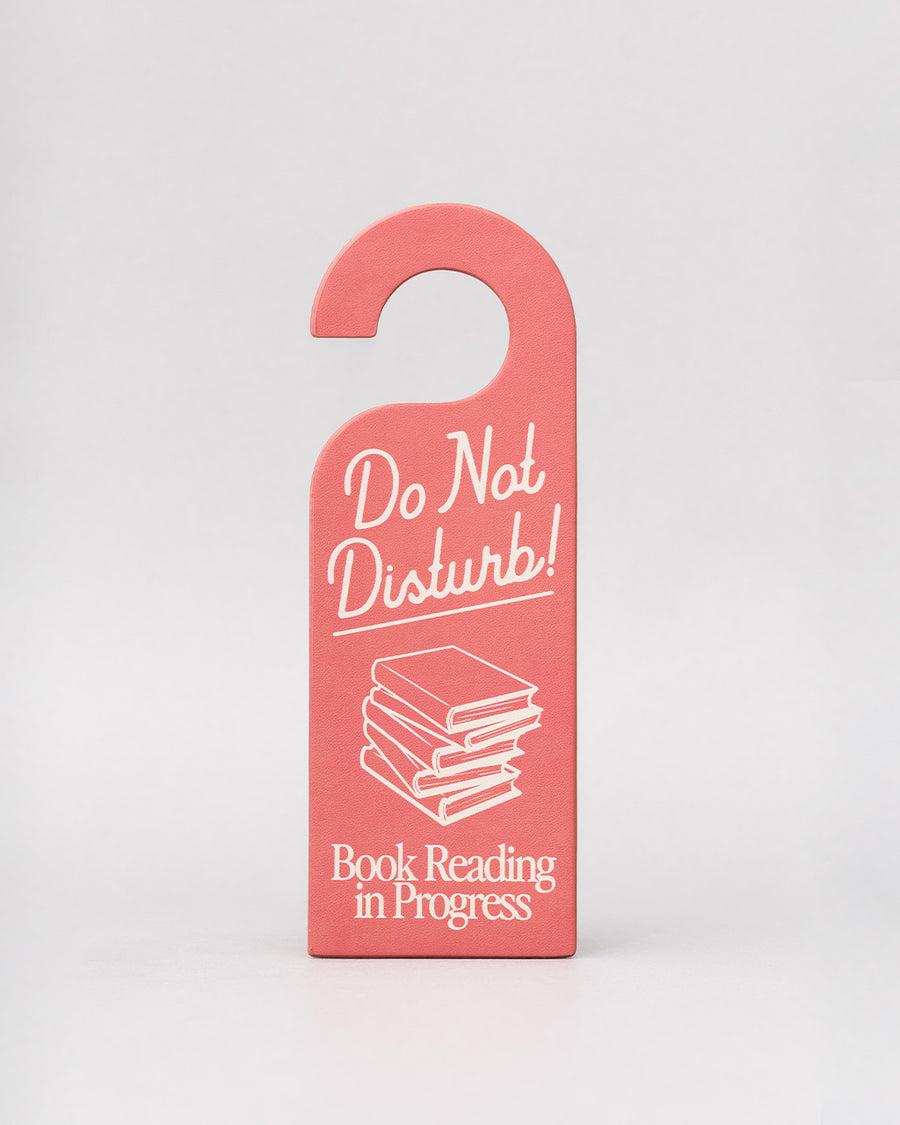 pink bookmark in the shape of a door hanger with white 'do not disturb! book reading in progress' across the front