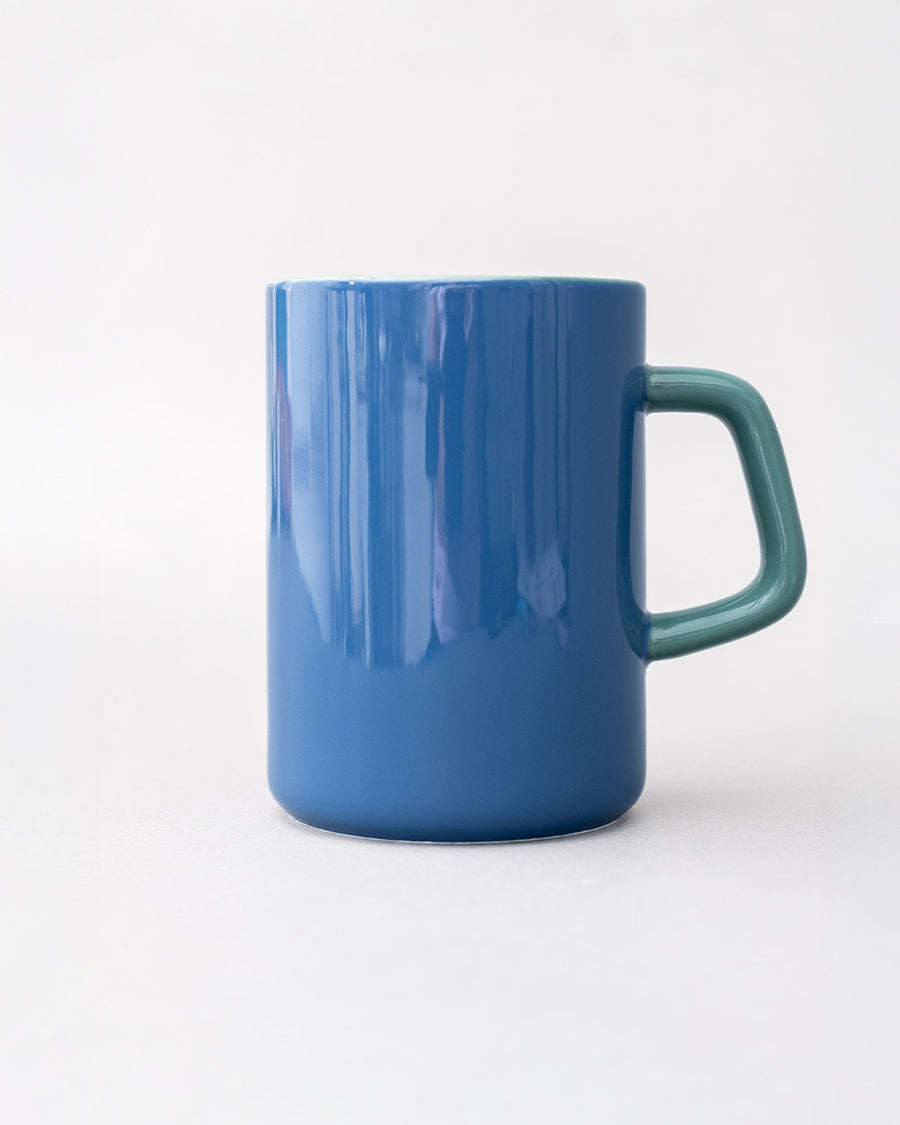 back view of blue ceramic mug with light pink heart and cursive' bookworm' across the front with teal handle and interior