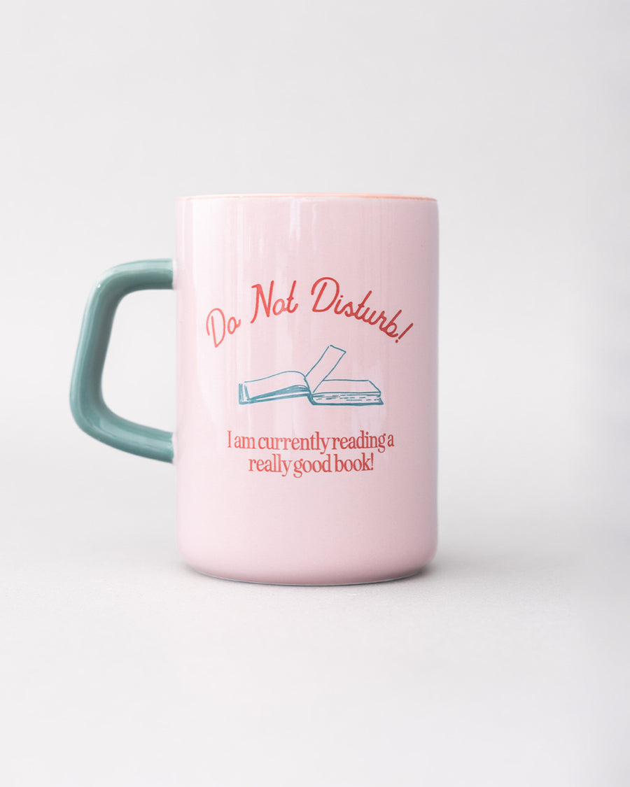 reversed side of light pink ceramic mug with teal handle and 'do not disturb! i am currently reading a really good book!' typography on both sides